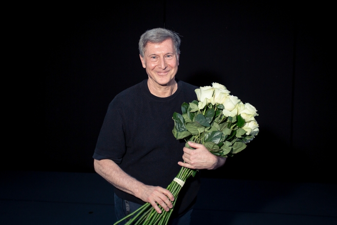 Martin Schläpfer freut sich und hält einen großen Strauß weißer Rosen.