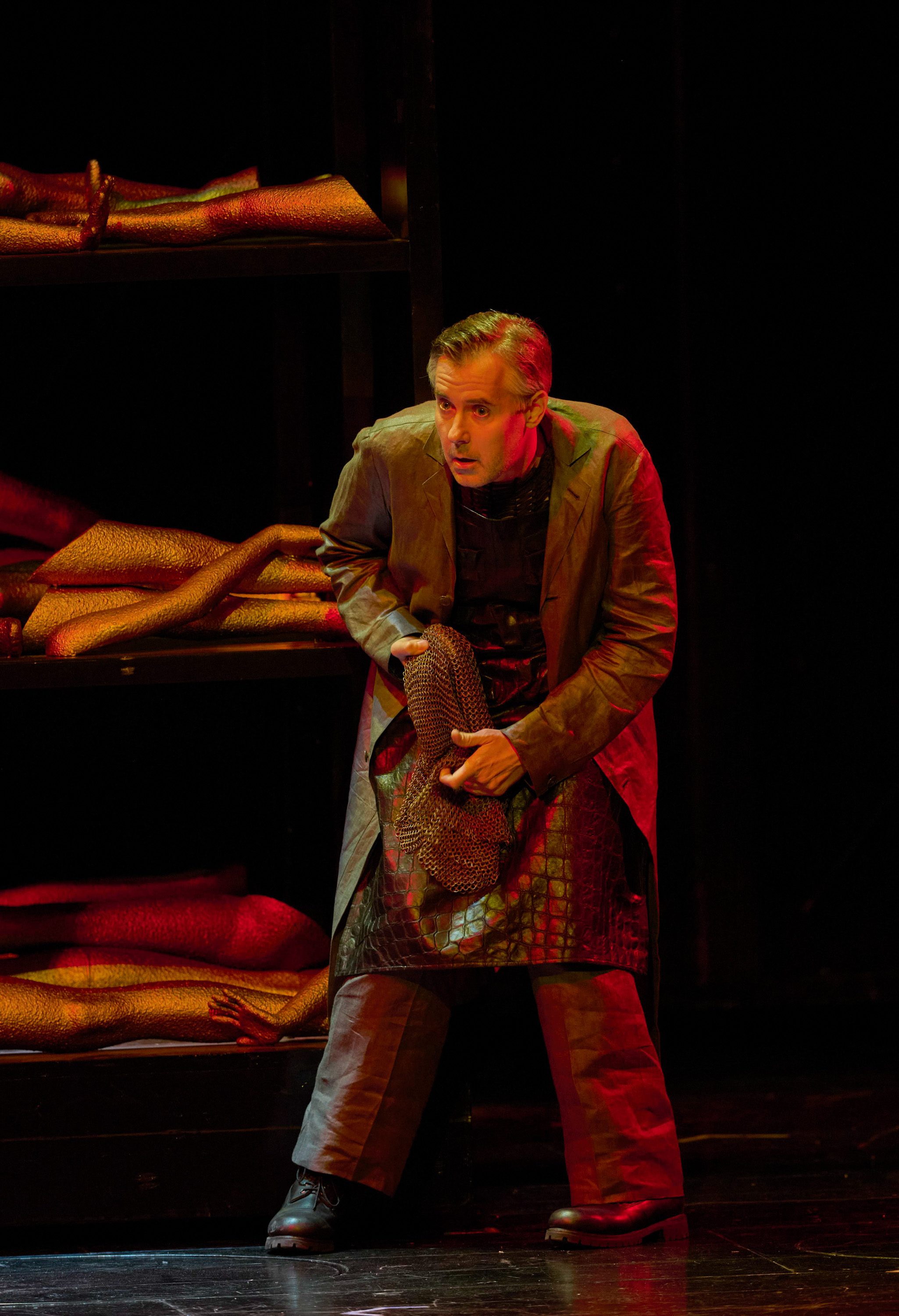 Ein Mann im Mantel duckt sich vor einem dunklen Hintergrund 