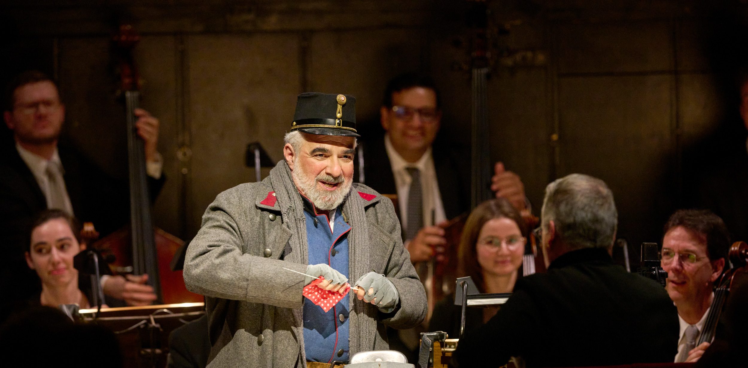 Ein älterer Mann in historischer Uniform lächelt und hält eine Fahrkarte in den Händen.