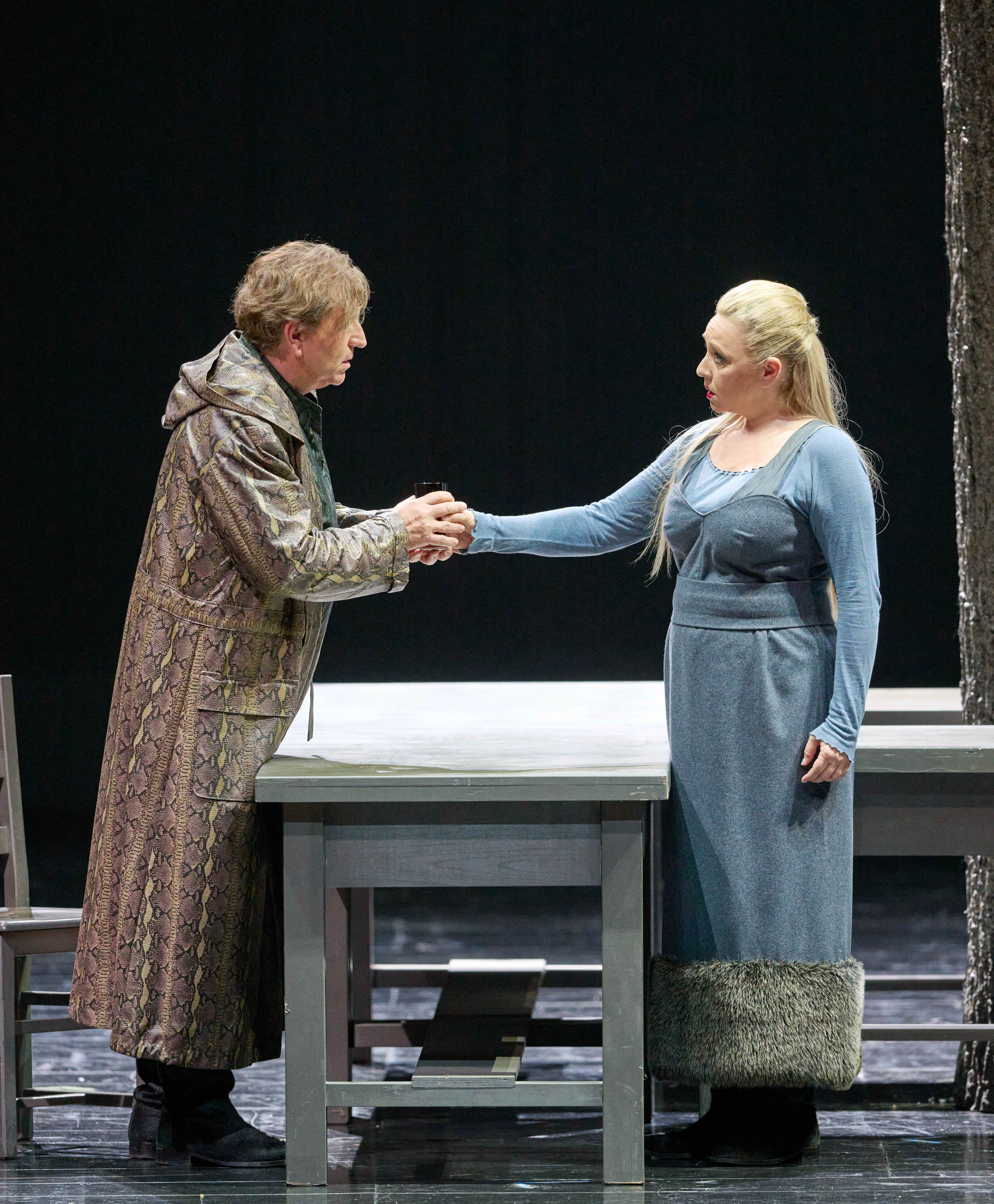 Ein Mann und eine Frau in mittelalterlicher Kleidung stehen sich an einem Tisch gegenüber und halten sich die Hände.